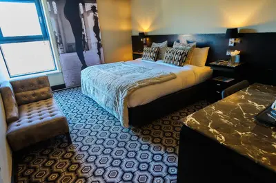 a bedroom with a bed and a chair and a window at The Vincent Hotel in Southport