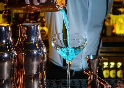 a bartender pouring a blue drink into a glass at The Vincent Hotel in Southport
