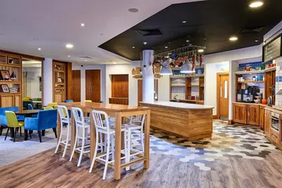 a restaurant with a bar with stools and a counter at Staybridge Suites Liverpool by IHG in Liverpool