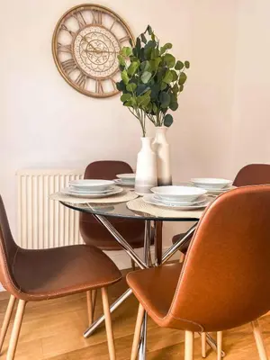 a dining room table with chairs and a vase with a plant at Sutton Heath Lodge in Saint Helens