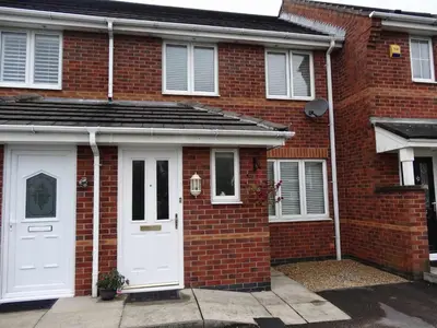 a red brick house with white doors and windows at Sutton Heath Lodge in Saint Helens