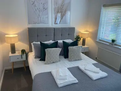a bedroom with a large bed with green and white pillows at Sutton Heath Lodge in Saint Helens