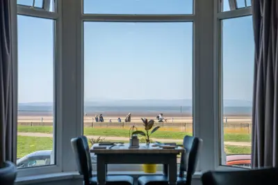 a dining room with a table and a view of the beach at The Clifton Seafront Hotel in Morecambe