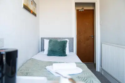 a bed with a blue pillow and two towels on it at The Clifton Seafront Hotel in Morecambe