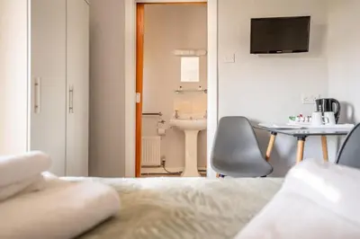a room with a bed and a table and a television at The Clifton Seafront Hotel in Morecambe