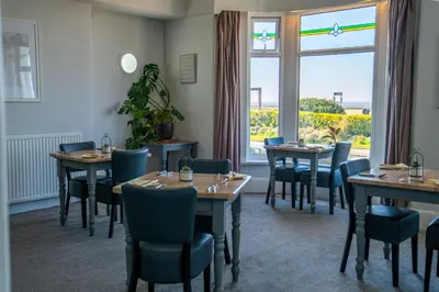 a dining room with tables and chairs and a window at The Clifton Seafront Hotel in Morecambe