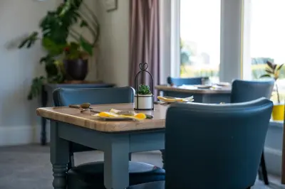a dining room table with blue chairs and a wooden table at The Clifton Seafront Hotel in Morecambe