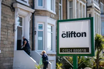 a sign in front of a building with people walking up the stairs at The Clifton Seafront Hotel in Morecambe