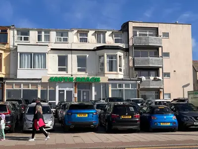 a woman walking past a parking lot in front of a building at South Beach Hotel in Blackpool