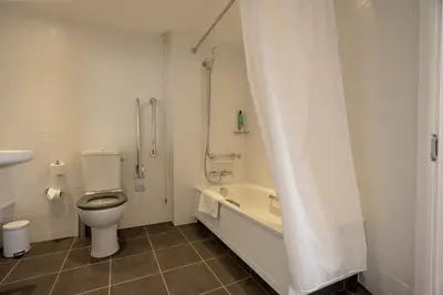 a bathroom with a toilet and a tub and a sink at Holiday Inn Preston by IHG in Preston
