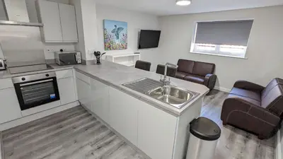 a kitchen with a sink and a living room at Cocoon @ International Inn + Apartments in Liverpool