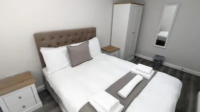 a bedroom with a large white bed with a wooden headboard at Cocoon @ International Inn + Apartments in Liverpool