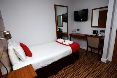 a hotel room with a bed and a desk and a television at Cocoon @ International Inn + Apartments in Liverpool