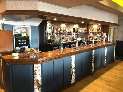 a bar with a long counter in a room at Tiffany's Hotel in Blackpool
