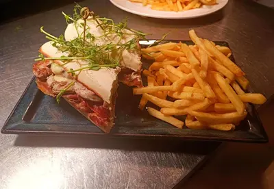 a black plate with a sandwich and french fries at Dukes Folly Hotel in Southport