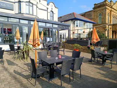 an outdoor patio with tables and chairs and umbrellas at Dukes Folly Hotel in Southport