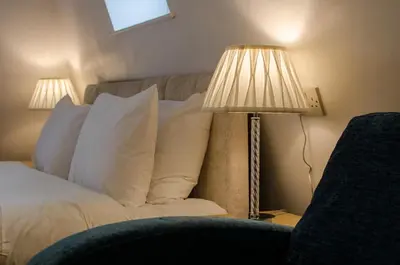 a bedroom with a bed with a lamp and a chair at Dukes Folly Hotel in Southport