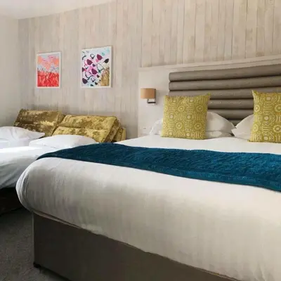 a hotel room with two beds with yellow and white pillows at St Ives Hotel in Lytham St Annes