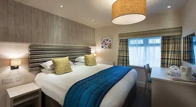 a bedroom with a large bed with a blue blanket at St Ives Hotel in Lytham St Annes