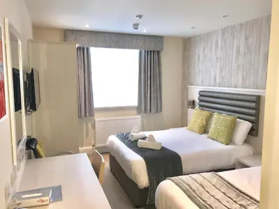 a hotel room with two beds and a window at St Ives Hotel in Lytham St Annes