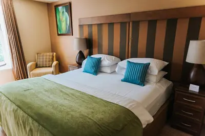a hotel room with a large bed with blue pillows at Spa Hotel at Ribby Hall Village in Wrea Green