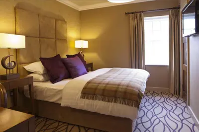 a bedroom with a bed with purple pillows and a window at Spa Hotel at Ribby Hall Village in Wrea Green