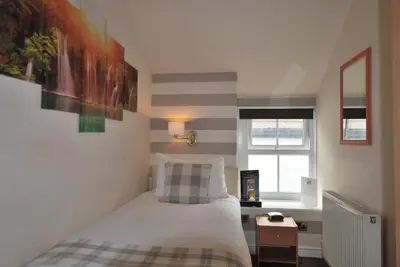 a small bedroom with a bed and a window at Ye Olde Fighting Cocks in Arnside