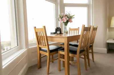 a dining room table with two chairs and a vase of flowers at Kelvin House in Fleetwood