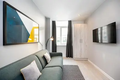 a living room with a green couch and a television at Staycity Aparthotels Liverpool Waterfront in Liverpool