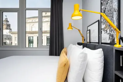 a bedroom with a white bed and a yellow lamp at Staycity Aparthotels Liverpool Waterfront in Liverpool