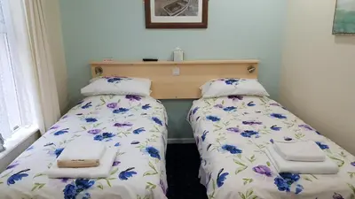 two beds in a small room with flowers at The Beverley Hotel in Blackpool