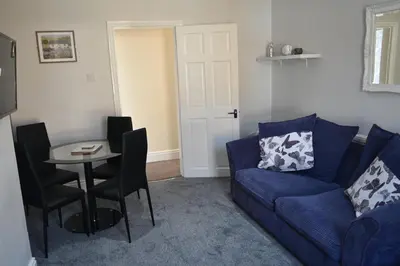 a living room with a blue couch and a table at Adelaide Apartments 2 in Blackpool