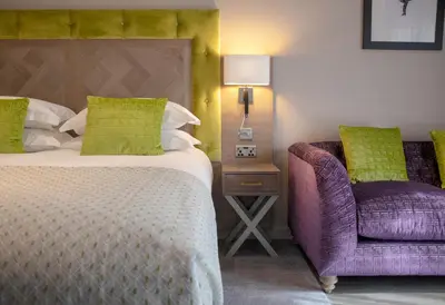 a bedroom with a bed and a purple chair at Boulevard Hotel in Blackpool