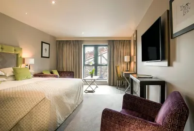 a hotel room with a bed and two chairs and a television at Boulevard Hotel in Blackpool