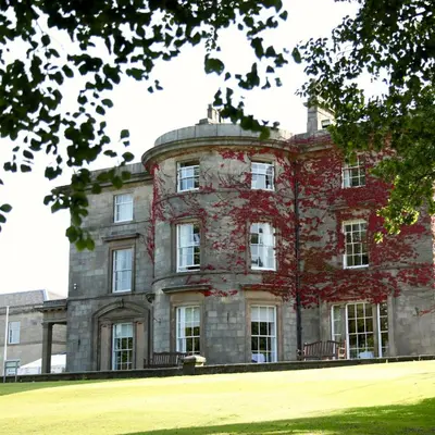 a large brick building with two benches in front of it at Shaw Hill Hotel Golf And Country Club in Chorley