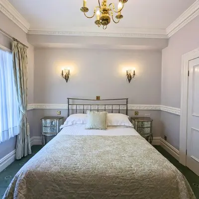 a bedroom with a large bed and a chandelier at Shaw Hill Hotel Golf And Country Club in Chorley