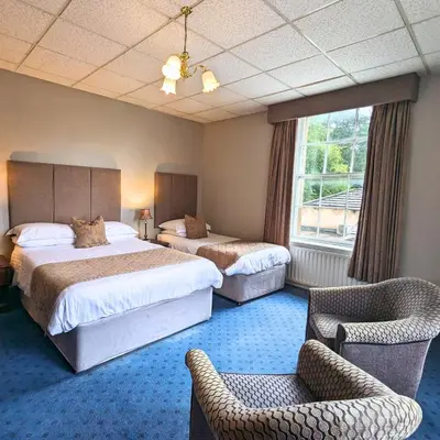 a hotel room with two beds and a chair at Shaw Hill Hotel Golf And Country Club in Chorley