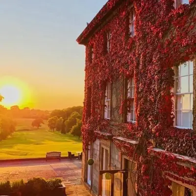 a building covered in ivy with the sunset in the background at Shaw Hill Hotel Golf And Country Club in Chorley
