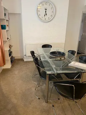 a glass table with chairs and a clock on the wall at 39 Cowley Road in Liverpool