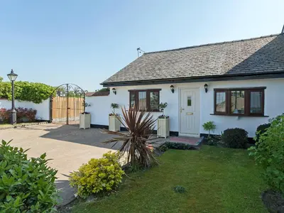 a white house with a yard with a courtyard at Buttercup Cottage in Halsall
