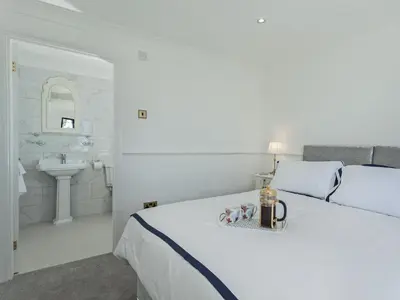 a white bedroom with a bed and a sink at Buttercup Cottage in Halsall