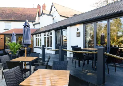 a patio with tables and chairs and an umbrella at Miller & Carter Aughton by Innkeeper's Collection in Ormskirk