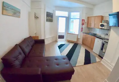 a living room with a couch and a kitchen at Empress Select Holiday Flats in Blackpool