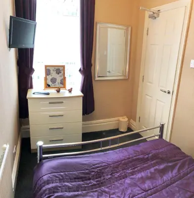 a bedroom with a bed and a dresser and a window at Empress Select Holiday Flats in Blackpool