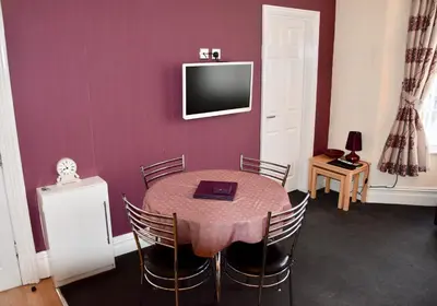 a dining room with a table and a tv on a wall at Empress Select Holiday Flats in Blackpool