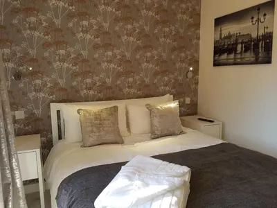 a bedroom with a white bed with a floral wallpaper at Sweet Suites Residence in Lytham St Annes