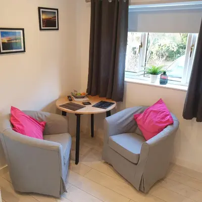 a living room with two chairs and a table and a window at Sweet Suites Residence in Lytham St Annes