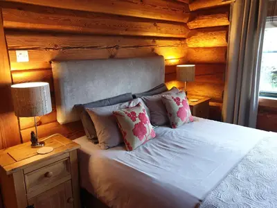 a bedroom with a bed with a wooden wall at Newland Valley Log Cabins in Ulverston