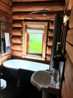 a bathroom with a tub and a sink and a window at Newland Valley Log Cabins in Ulverston