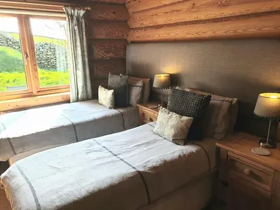 a bedroom with two beds and a window at Newland Valley Log Cabins in Ulverston